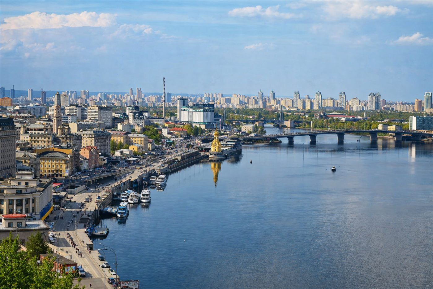 Aerial panorama of Kyiv with the Dnipro river, Podil embankment, and the east bank cityscape under clear skies